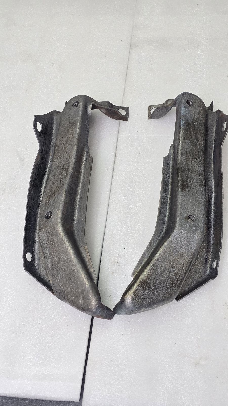 The same two brackets stripped to clean bare steel