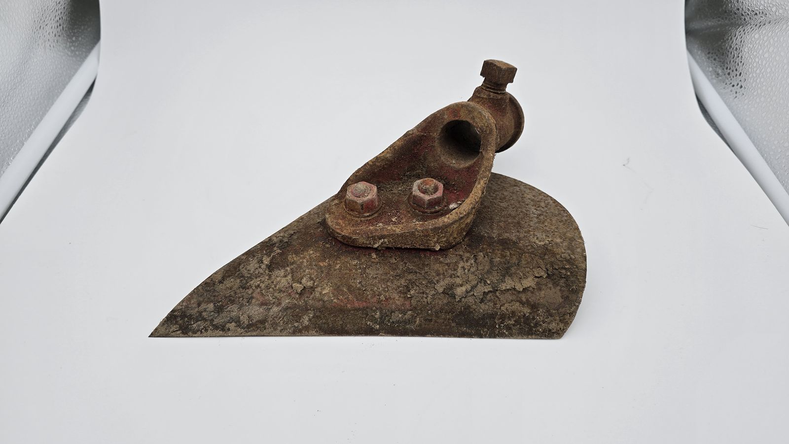 Rusty cast wedge part with seized, corroded bolts before laser blasting