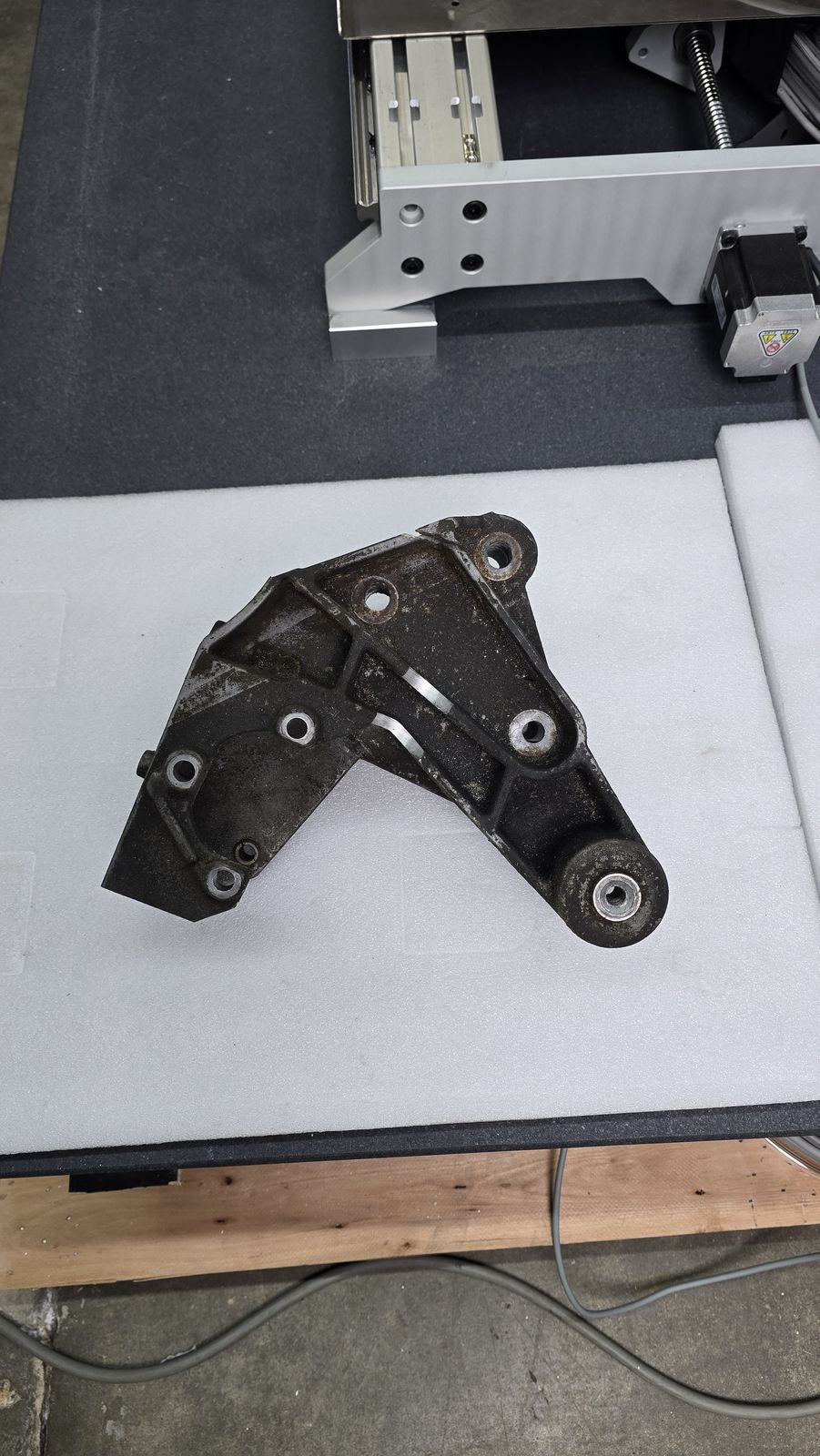 Cast automotive bracket with mounting holes before laser blasting