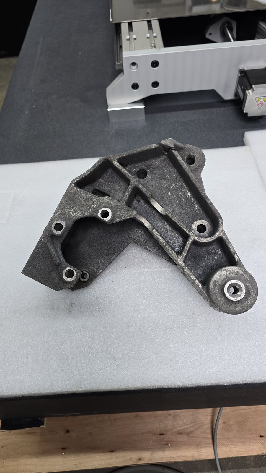 Machined bracket with multiple holes and channels, cleaned by laser without clogging